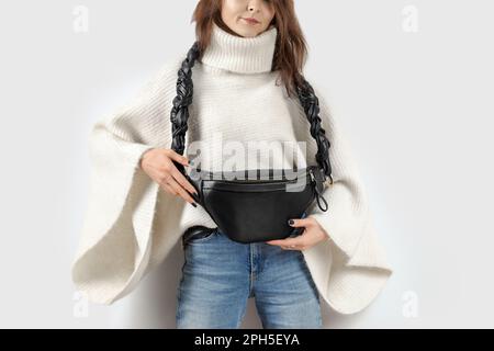 Frau mit Gürteltasche aus schwarzem echtem Leder und wunderschönem geflochtenem Riemen. Handgefertigtes Leder Accessoires Stockfoto