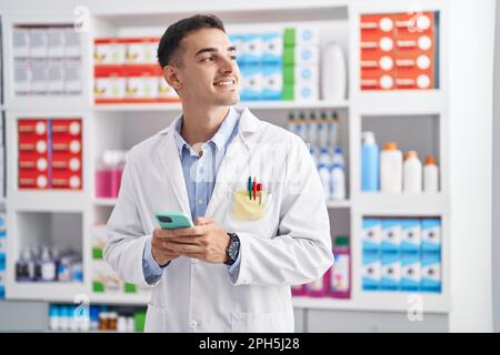 Junger hispanic-Mann Apotheker mit Smartphone in der Apotheke arbeiten Stockfoto