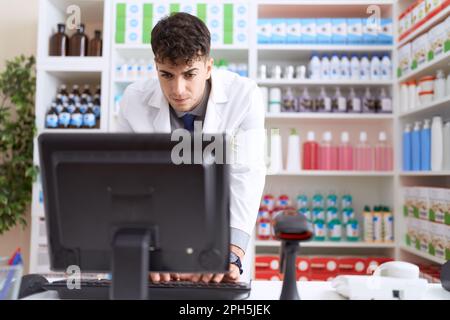 Junger hispanischer Apotheker mit Computer in der Apotheke Stockfoto