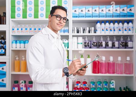Junger hispanischer Apotheker, der auf einem Dokument in der Apotheke schreibt Stockfoto