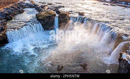 Godafoss Wasserfall im Sonnenlicht. Dröhnchenaufnahme mit der Breite der 30 Meter langen Hufeisenspannen. Einer der glänzendsten Wasserfälle in Eis Stockfoto