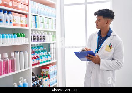 Junger hispanischer Apotheker, der auf einem Dokument in der Apotheke schreibt Stockfoto