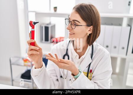 Junge Kaukasierin, die Otoskop in der Klinik hält Stockfoto