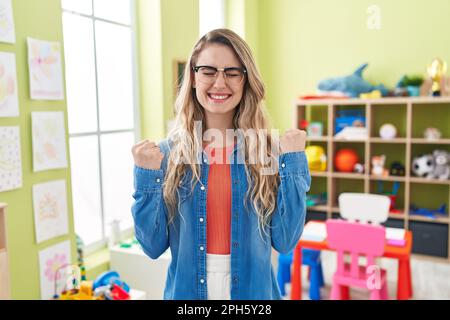 Junge weiße Frau, die als Lehrerin im Kindergarten arbeitet, schreit stolz, feiert den Sieg und Erfolg mit erhobenen Armen Stockfoto