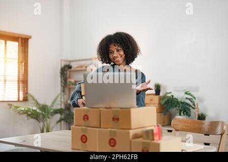 Porträt von kleinen Unternehmen, kleinen und mittleren Unternehmen, afroamerikanische Frau, Videoanruf, Online-Bestellungen prüfen, Produkte verkaufen, die mit Box Freelance arbeiten Stockfoto