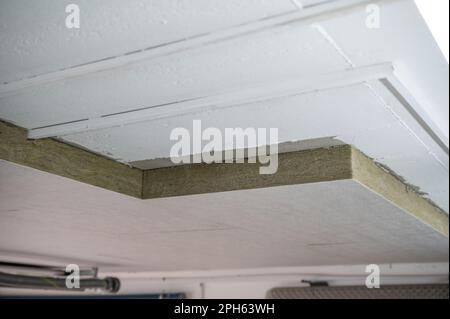 Dämmplatten aus Mineralwolle, die unter einer Untergeschossdecke verklebt wurden Stockfoto