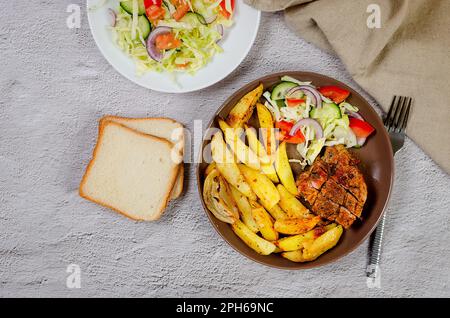 Gebratene Rippchen mit gebackenen Kartoffeln und Gewürzen auf dem Teller für ein leckeres Mittagessen. Gebackenes Schweinefleisch mit Gemüse im Backofen. Stockfoto