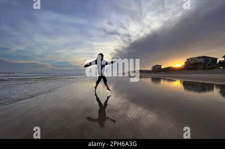 Surf City, North Carolina, USA. 25. März 2023. CLAUDIA FONSECA springt bei Sonnenuntergang über den Strand von Surf City in North Carolina (Kreditbild: © Bob Karp/ZUMA Press Wire) – NUR REDAKTIONELLE VERWENDUNG! Nicht für den kommerziellen GEBRAUCH! Stockfoto