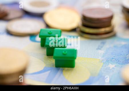 Kleines Haus in Münzstapeln, die die Hausfinanzierung darstellen Stockfoto