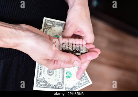 Das Mädchen hat ein Portemonnaie in der Hand, beim Einkaufen, Dollar in der Handtasche, eine Brieftasche voller Dollar Stockfoto