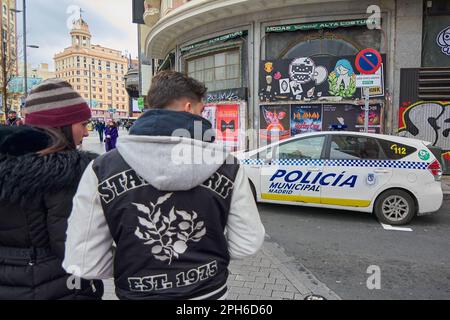 MADRID, SPANIEN - 26. März 2023: Ein junges Paar, das auf der gran Via in Madrid auf einem geparkten Polizeiauto steht Stockfoto