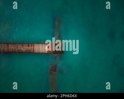 Holzpier im Meer. Blick von oben. Minimalismus. Abstraktion. Schwimmen, Tauchen, Angeln, Bootsfahrten. Einsamkeit, Romantik. Stockfoto