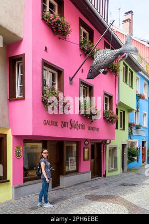 Lindau, Deutschland - 19. Juli 2019: Straße mit farbigen Häusern in der Altstadt von Lindau, weibliche Touristen gehen im Sommer an Fischrestaurant vorbei. Sie Stockfoto