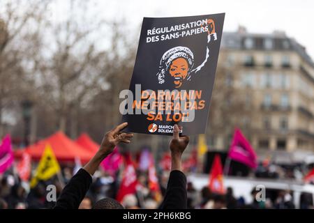 Paris, Frankreich. 25. März 2023. Ein Protestteilnehmer hält während einer Demonstration gegen das Gesetz Darmanins ein Plakat mit der Aufschrift "Darmanin ne fera pa sa loi". Tausende von französischen Migranten und Migranten ohne Papiere marschierten gemeinsam gegen dieses Gesetz des französischen Innenministers Gerald Darmanin, das das Recht auf Asyl weiter einschränken, Einwanderer in prekären Verhältnissen kriminalisieren und den Anteil der Arbeitskräfte erhöhen will, die gezwungen werden können, zu arbeiten und nach Belieben deportiert werden können. Kredit: SOPA Images Limited/Alamy Live News Stockfoto