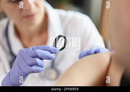 Dermatologe mit Lupe untersucht die Haut des Patienten Stockfoto
