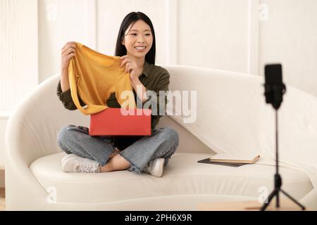 Weibliche Beeinflusserin, junge asiatische Frau, die Produktwäsche, Streaming überprüft Stockfoto