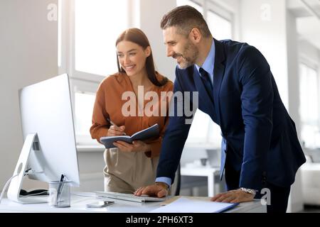 Geschäftskollegen, die Computer nutzen und kommunizieren, gemeinsam an einem Unternehmensprojekt arbeiten, Ideen im Büro besprechen Stockfoto