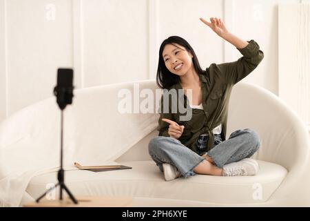 Süße asiatische Vloggerin tanzt, nimmt Inhalte für Follower auf Stockfoto