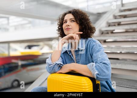 Reiseplan. Pensive Junge Frau Mit Koffer, Die Am Flughafen Wartet Stockfoto