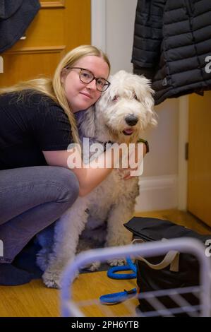 Eine junge Frau umarmt ihren pelzigen Freund, einen alten englischen Schäferhund, in einer liebevollen Umarmung. Stockfoto