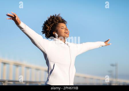 Freiheitskonzept. Junge, Sportliche Schwarze Frau, Die Die Augen Schließt Und Arme Im Freien Verteilt Stockfoto