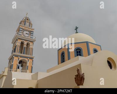 Der Turm mit Uhr und Kuppel der Kathedrale von St. Johannes der Täufer in Fira, Santorin an einem bewölkten Tag Stockfoto