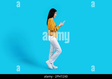 Profilaufnahme einer asiatischen Frau mit Smartphone Stockfoto