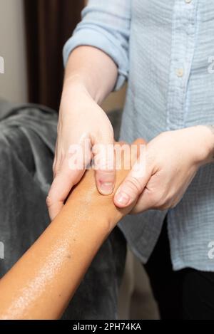 Massagetherapeutin starke Hände und Daumen üben direkten Druck auf die Handmuskulatur des Kunden aus, um eine totale Linderung zu erzielen. Stockfoto