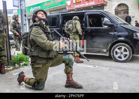 Nablus, Palästina. 26. März 2023. Israelische Soldaten nehmen nach einem Schussanschlag auf zwei israelische Soldaten in der Stadt Hawara, südlich von Nablus, im besetzten Westjordanland ihre Positionen ein. Unruhen zwischen Palästinensern, jüdischen Siedlern und israelischen Soldaten in der Stadt Hawara, nachdem die Siedler ein hartes Vorgehen gegen Palästinenser forderten, nachdem ein Palästinenser das Feuer auf einen Militärposten eröffnete und zwei israelische Soldaten verletzte. Das ist der dritte Schussanschlag in der Stadt diesen Monat. Kredit: SOPA Images Limited/Alamy Live News Stockfoto