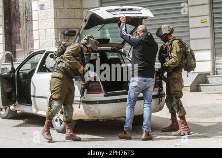 Nablus, Palästina. 26. März 2023. Israelische Soldaten durchsuchen palästinensische Autos nach einem Schussanschlag auf zwei israelische Soldaten in der Stadt Hawara südlich von Nablus im besetzten Westjordanland. Unruhen zwischen Palästinensern, jüdischen Siedlern und israelischen Soldaten in der Stadt Hawara, nachdem die Siedler ein hartes Vorgehen gegen Palästinenser forderten, nachdem ein Palästinenser das Feuer auf einen Militärposten eröffnete und zwei israelische Soldaten verletzte. Das ist der dritte Schussanschlag in der Stadt diesen Monat. Kredit: SOPA Images Limited/Alamy Live News Stockfoto