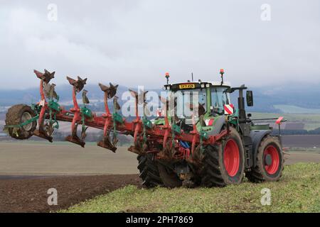 Ein Fendt Traktor mit einem Kverneland Variomat 3400 S Wendepflug auf einem Wiesenfeld (Gründung) während des Pflügen im Frühjahr Stockfoto