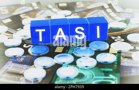 Euro-Banknoten und -Münzen mit dem Text auf den Blöcken ‚Tasi‘. Der Begriff der italienischen Steuer. Stockfoto