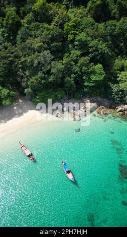 Zwei kleine Boote liegen am Strand neben ruhigen grünen Gewässern und unberührtem weißen Sand Stockfoto