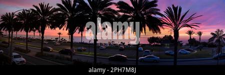 Sonnenuntergang an der Westküste über einem Parkplatz mit Autos, Palmen und dem Pazifik in Dana Point, Orange County, Südkalifornien. Stockfoto