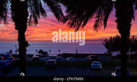 Sonnenuntergang an der Westküste über einem Parkplatz, Palmen, dem Pazifischen Ozean mit Santa Catalina Island im Hintergrund. Das Foto wurde in Dana Point aufgenommen. Stockfoto