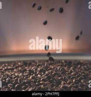 Geröstete Kaffeebohnen, die in ein Gericht voller Bohnen fallen Stockfoto