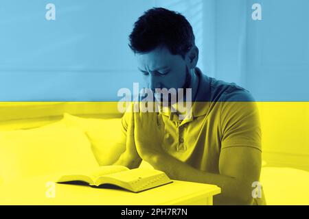 Bete für die Ukraine. Doppelbelichtung eines Menschen mit Bibelbeten im Raum und ukrainischer Nationalflagge Stockfoto