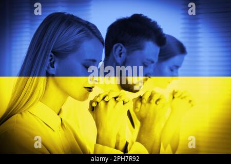 Bete für die Ukraine. Doppelte Exposition von Menschen, die gemeinsam beten, und ukrainischer Nationalflagge Stockfoto