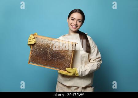 Imker in einheitlichem Bienenstockrahmen mit Wabenstruktur auf hellblauem Hintergrund Stockfoto