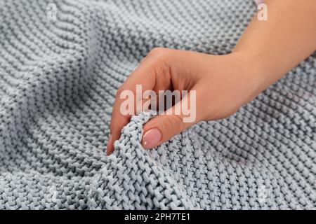 Frau berührt weichen grauen Strickstoff, Nahaufnahme Stockfoto