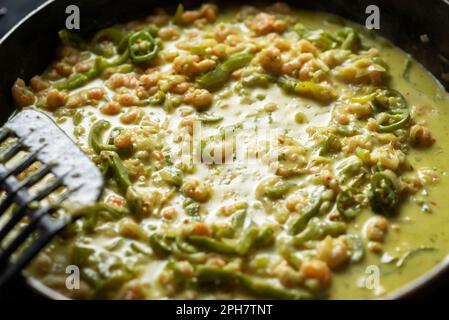 Garnelen, Gemüse und Sahne in einer Bratpfanne. Zubereitung von Shrimps-Spaghetti-Sauce mit Gewürzen. Stockfoto