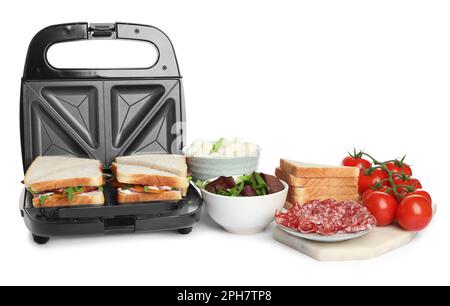 Moderne Grillmaschine mit Sandwiches und verschiedenen Produkten auf weißem Hintergrund Stockfoto