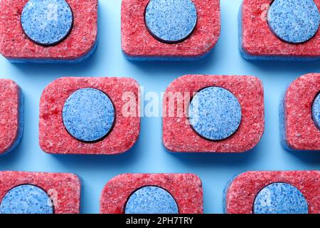 Viele Geschirrspülmitteltabletten auf hellblauem Hintergrund, flach liegend Stockfoto