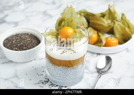 Köstlicher Chia-Pudding mit Physalis-Früchten auf einem weißen Marmortisch Stockfoto