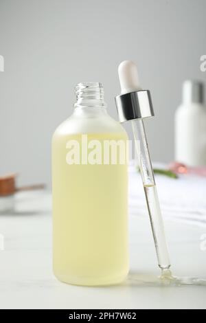 Flasche mit hydrophilem Öl und Pipette auf weißem Tisch Stockfoto