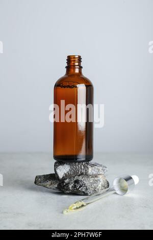 Flasche mit hydrophilem Öl, Steinen und Pipette auf weißem Tisch Stockfoto