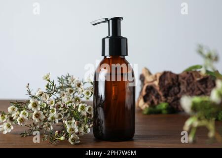 Eine Flasche hydrophiles Öl und wunderschöne Blumen auf einem Holztisch Stockfoto