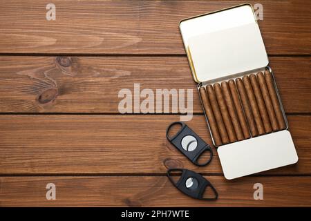 Humidor mit Zigarren und Schneidezähnen auf Holztisch, flach liegend. Platz für Text Stockfoto