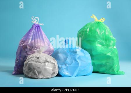 Verschiedene Müllsäcke voller Müll auf hellblauem Hintergrund Stockfoto