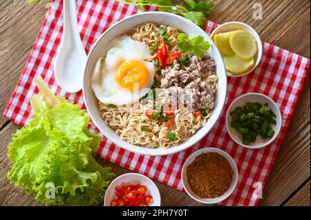 Nudelschüssel mit gekochtem Ei Hackfleisch Schweinefleisch Gemüse Frühlingszwiebeln Zitrone Limette Salat Sellerie und Chili auf dem Tisch Essen, Instantnudeln kochen leckeres Essen Stockfoto